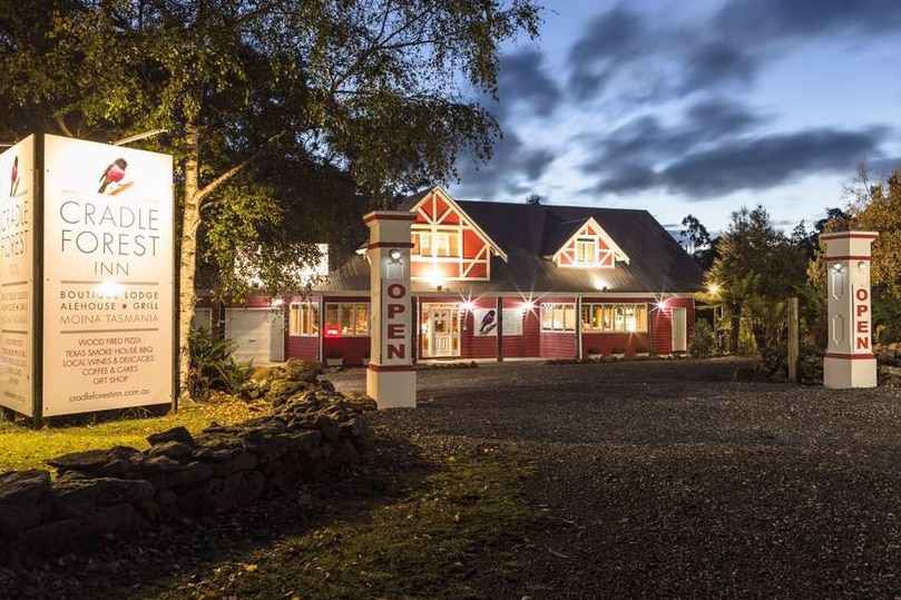 Lights shine in the windows and around a red lodge at sunset.