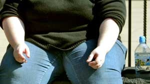 Overweight woman sitting on wall