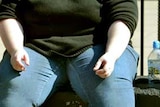 Overweight woman sitting on wall