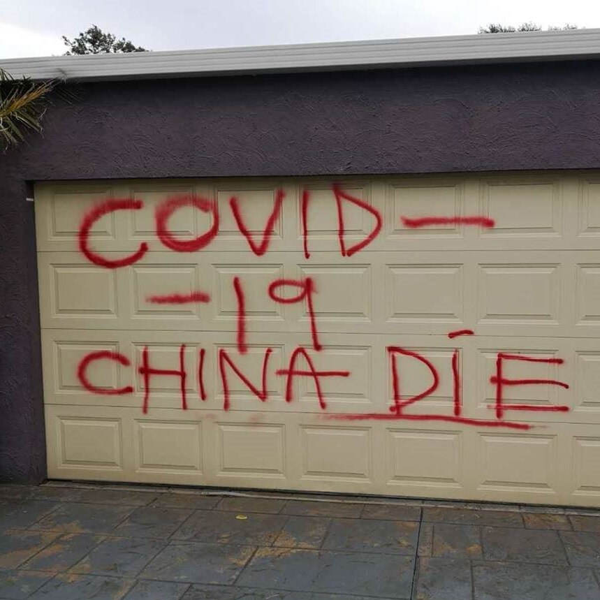 The words 'COVID-19 CHINA DIE' are spray painted in red on a garage door in a Melbourne suburb.