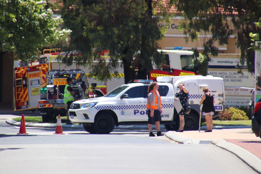 A police car blocks the road, with a fire truck pulled up nearby.