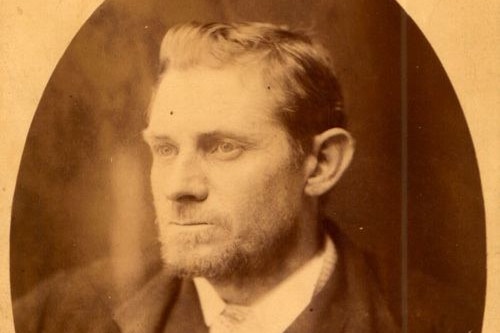 An old sepia toned photograph of a man in a suit looking out of frame.