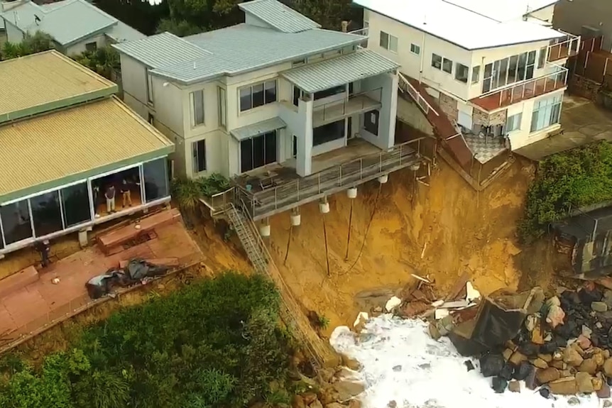 House foundations exposed and patios collapsed after surf ate away at the cliffs under homes