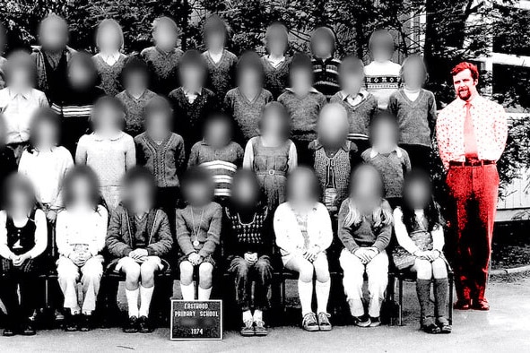 Bob Morris stands among rows of children in a primary school photo. The faces of the kids are blurred