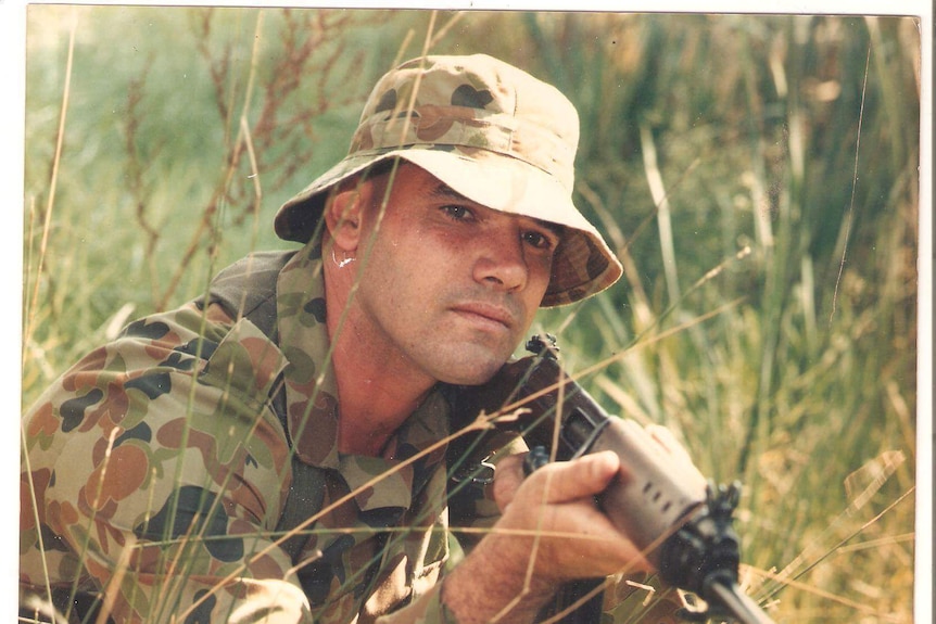 Ricky Morris in an army uniform holding a gun.