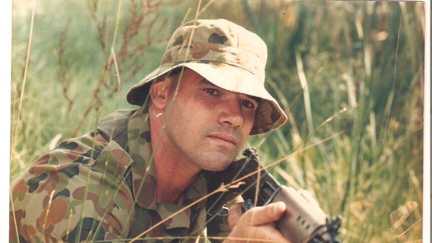 Ricky Morris in an army uniform holding a gun.