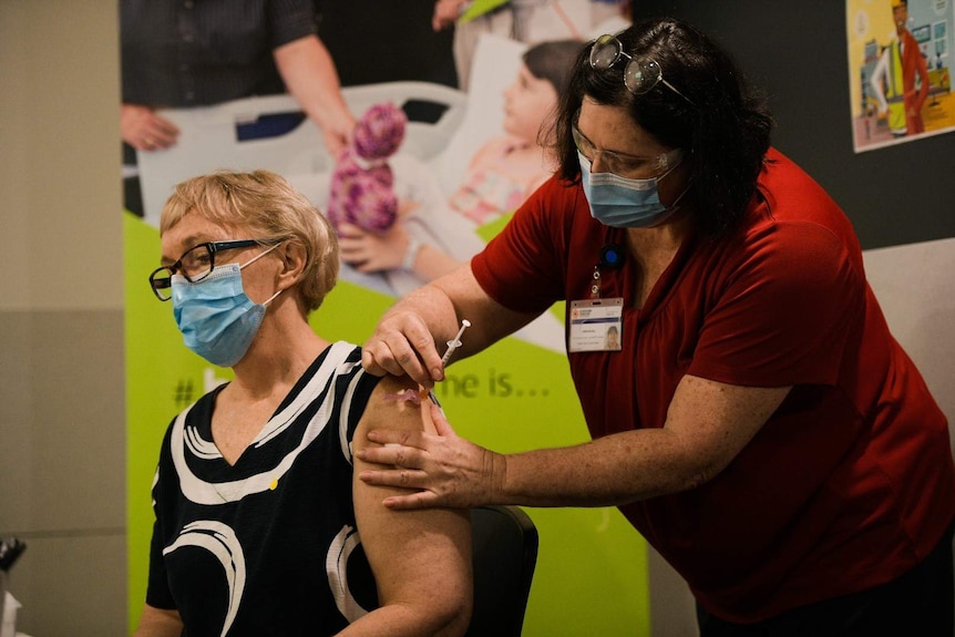 NT Deputy Chief Health Officer Di Stephens receives a COVID-19 vaccine from a nurse.