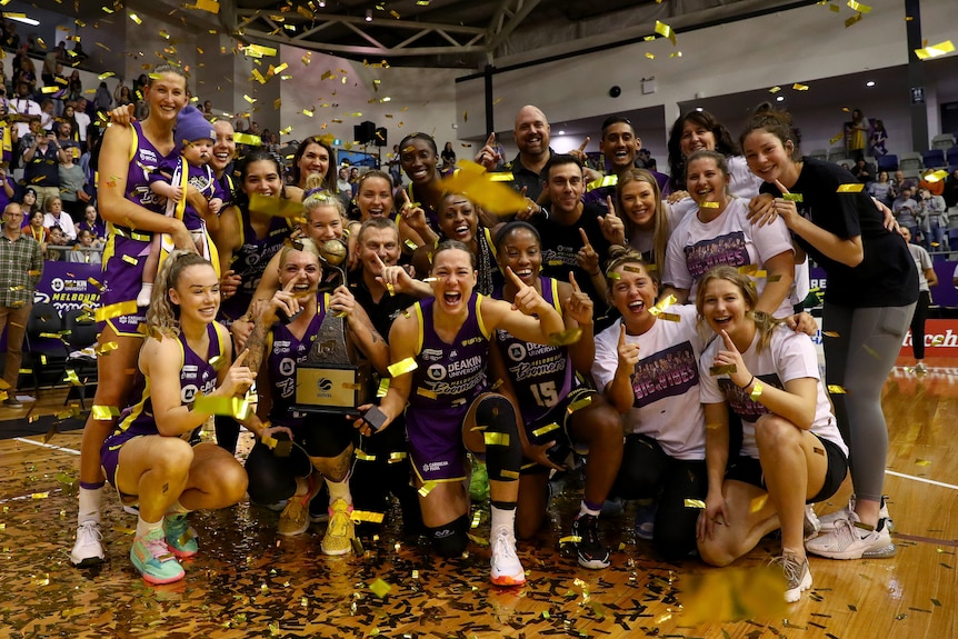 The Melbourne Boomers players in a group shot with the WNBL trophy celebrating their win.