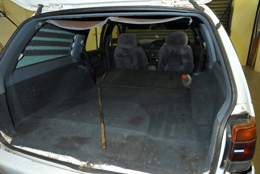 The open boot inside a white car parked in a room, which appears to be some kind of lab.