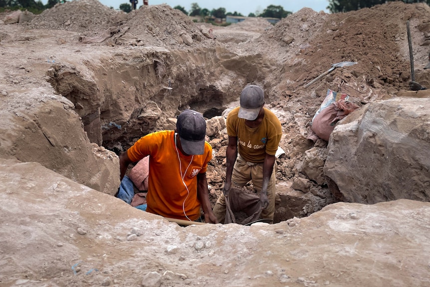 Men lift a sack of cobalt. 