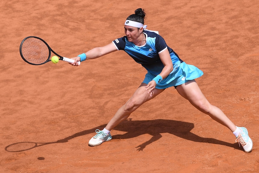 Ons Jabeur stretches for a shot on clay.