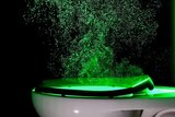 fluorescent green light shows the small particles coming out of a flushing toilet