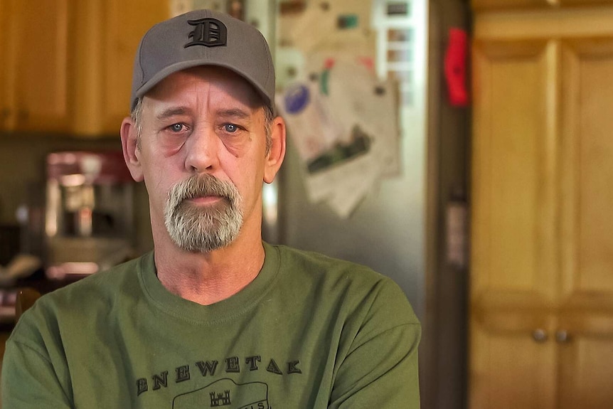 Jim Androl sits in his kitchen wearing a baseball cap.