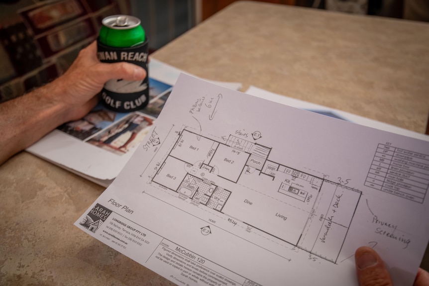 A hand holds a property plan.