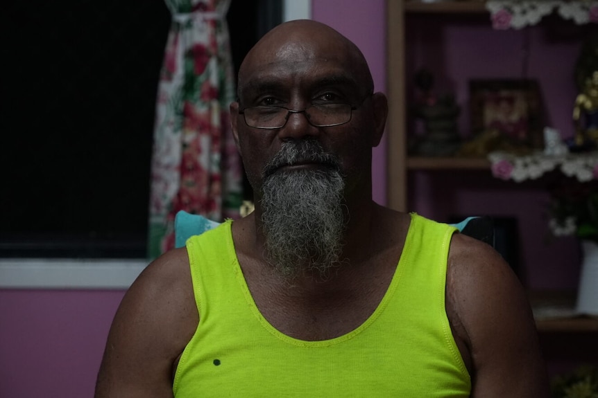 An Indigenous man with glasses and a yellow fluoro singlet.