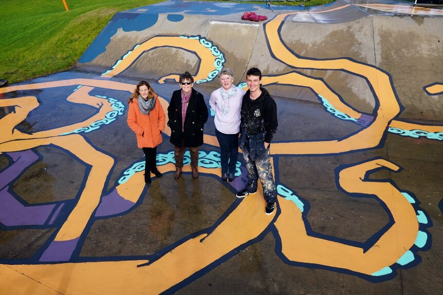 Artist Kitt Bennett stands with three members of the Imagine Millicent group on the finished skatepark mural.