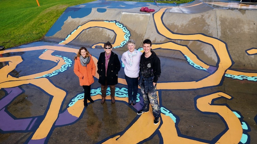 Artist Kitt Bennett stands with three members of the Imagine Millicent group on the finished skatepark mural.