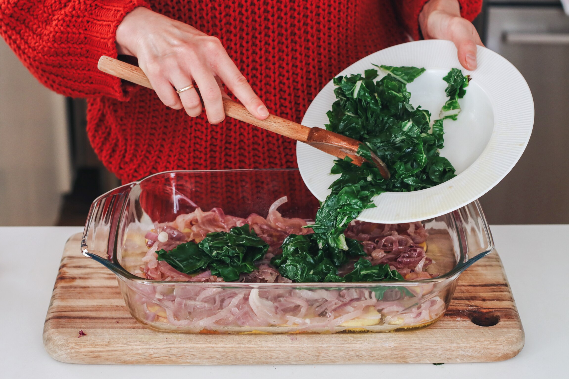 Heidi Sze spoons silverbeet on top of caramelised onions while preparing her baked frittata.