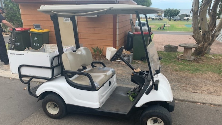 A white and black golf buggy parked on a road