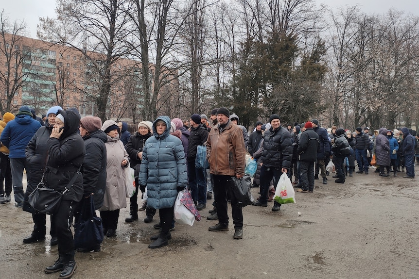 Local residents queue to receive food at the territory of a hospital.