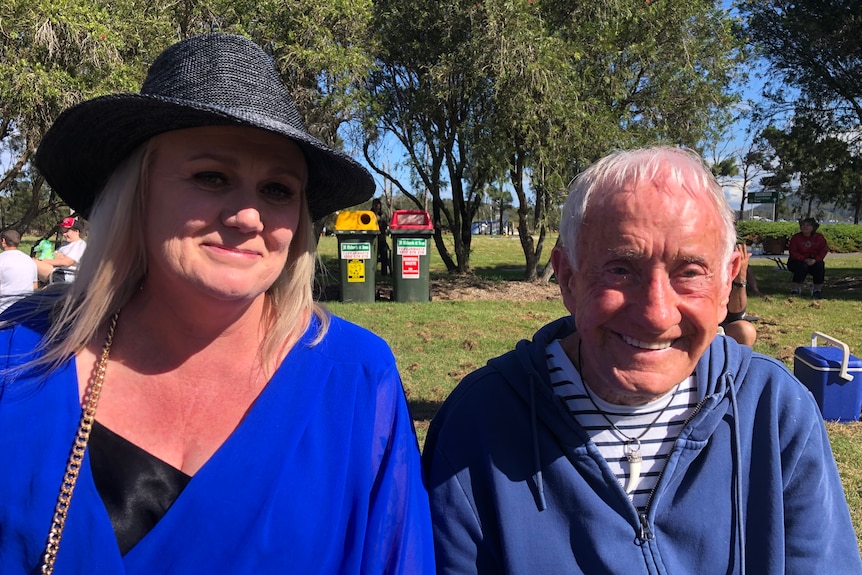 A woman wearing a black hat and bright blue jumper smiling with an older man in a blue parker.