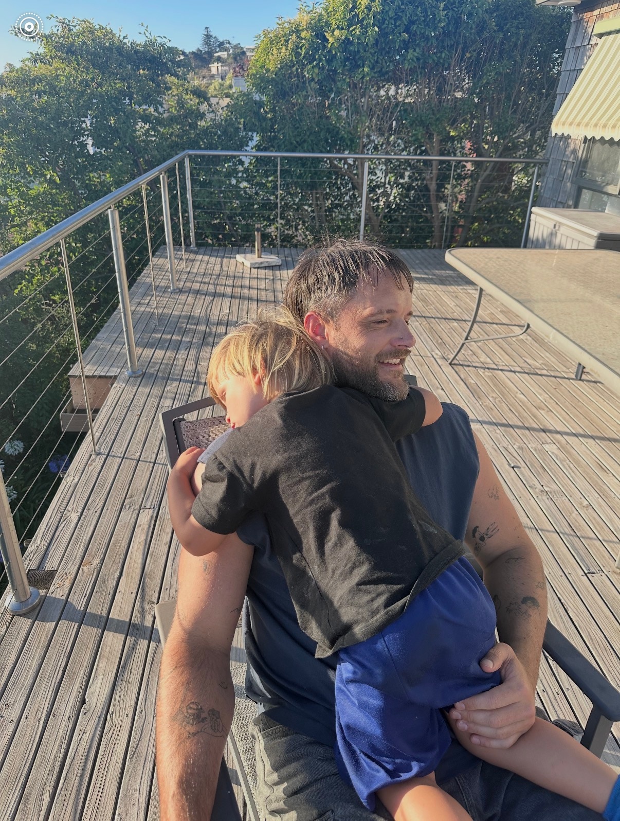 Mitch Brown está sentado em uma varanda com uma criança loira abraçada em seu colo