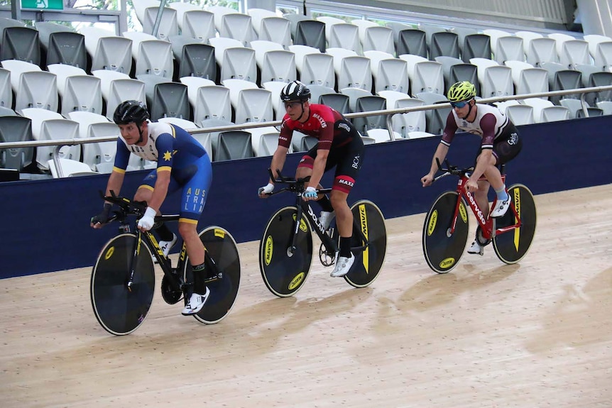 World champion track cyclist Jordan Kerby (in blue) rides ahead of two other cyclists on a track in Brisbane.