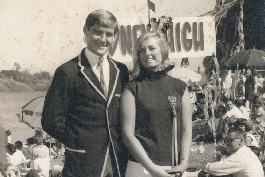 A man wearing a blazer and a woman wearing a rosette smile for the camera. 