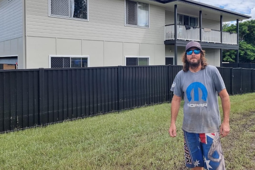 A man standing outside his flooded house.