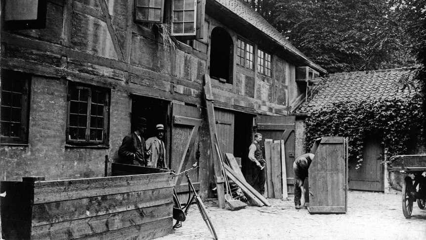 Wide black and white archive shot of men working on a house.