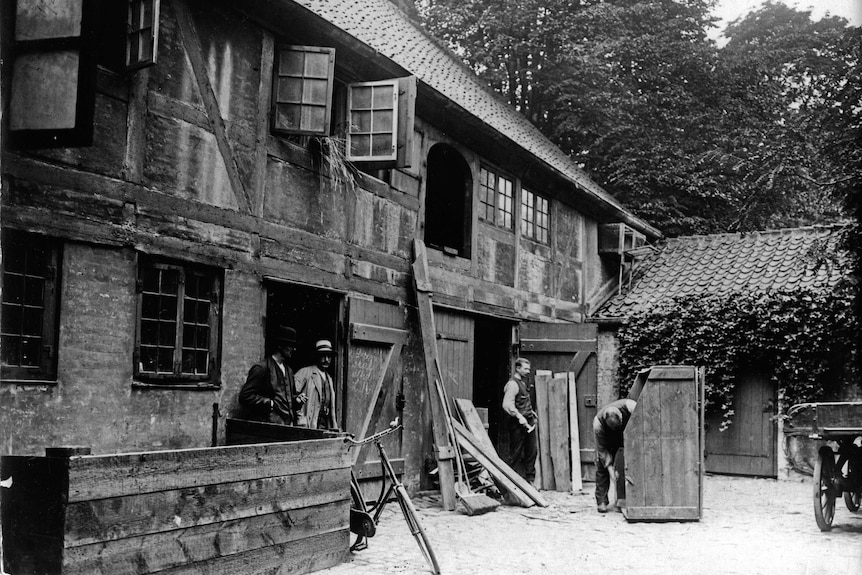 Wide black and white archive shot of men working on a house.