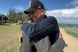 A man in a black cap hugging another man