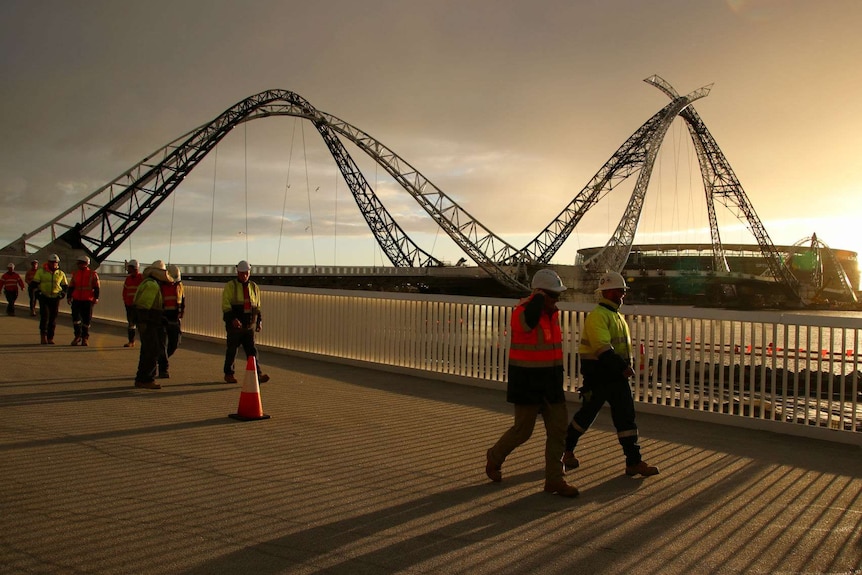 workers in high viz walking across Matagarup Bridge