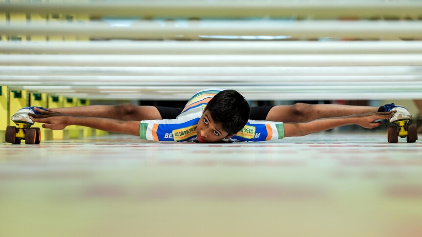 Rohan Ajit Kokane flattens his body as he skates under poles.