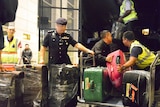 Police load suitcases and other confiscated items into a truck in Kuala Lumpur