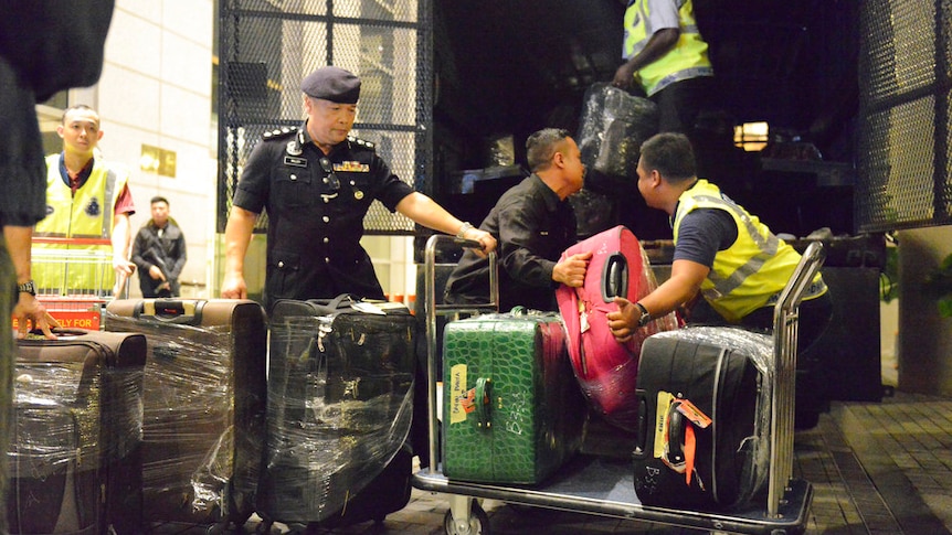 Police load suitcases and other confiscated items into a truck in Kuala Lumpur