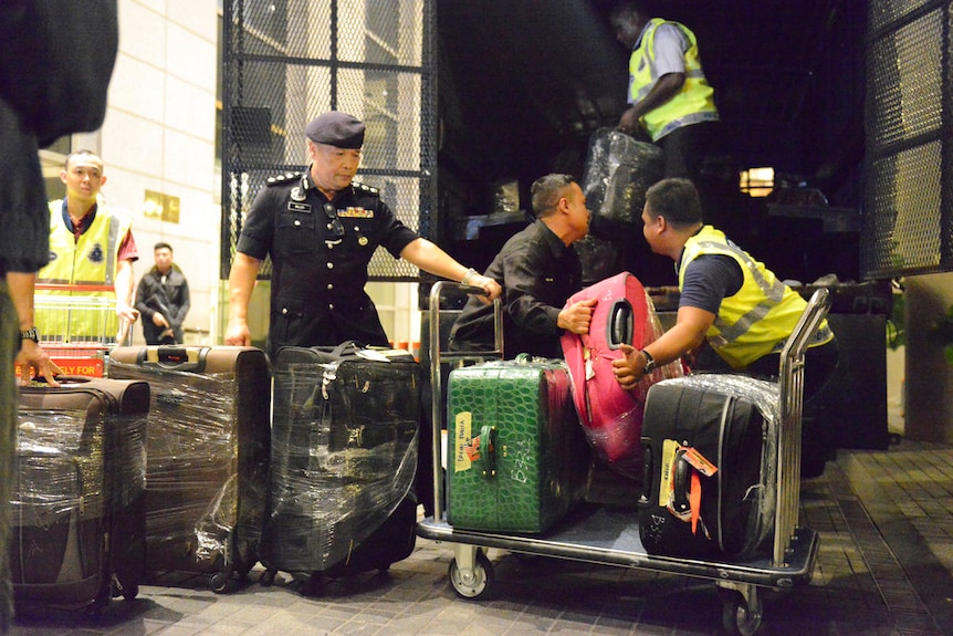 Police load suitcases and other confiscated items into a truck in Kuala Lumpur