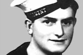 A young man wearing a sailor's uniform poses for a portrait. The photo is in black and white, clearly aged.