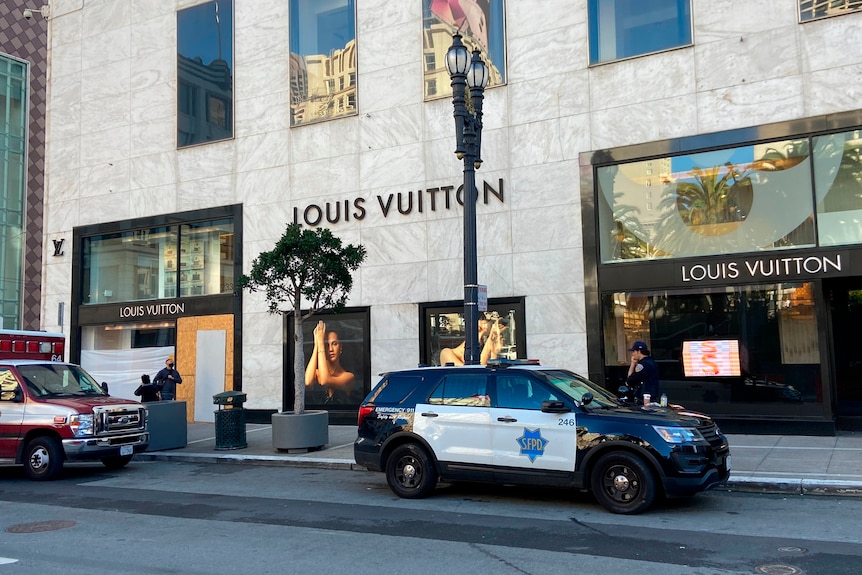 An exterior shot of a Louis Vuitton store with a door and window boarded up. 