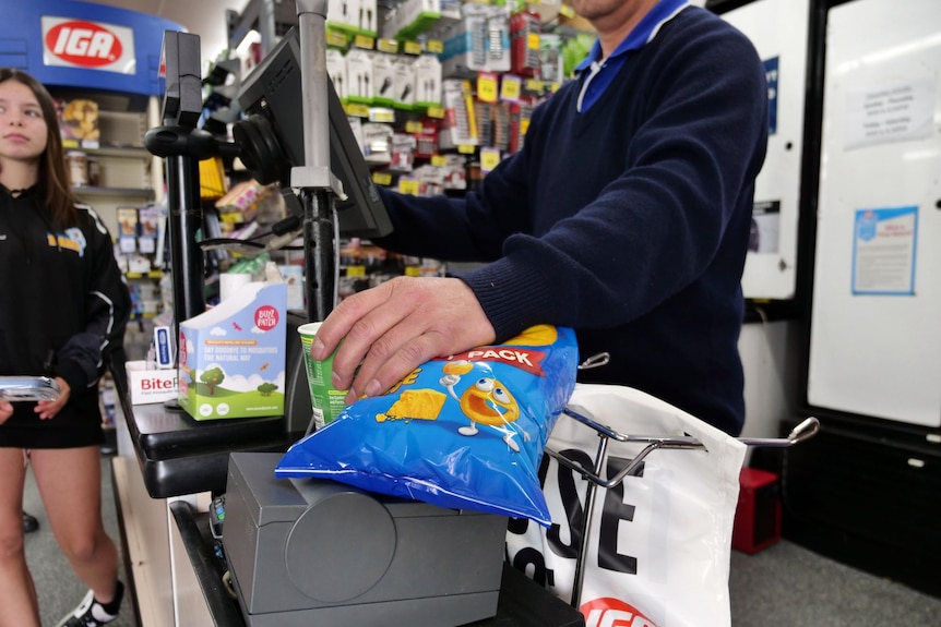 A man scans groceries through the register.