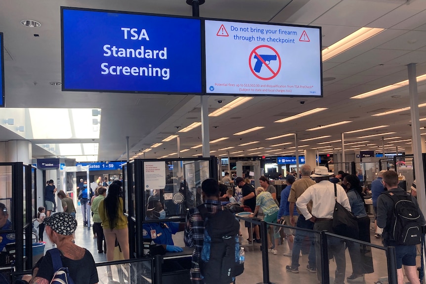 An airport security screening area with a sign which says TSA Standard Screening