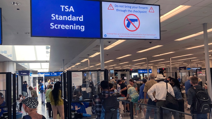 An airport security screening area with a sign which says TSA Standard Screening