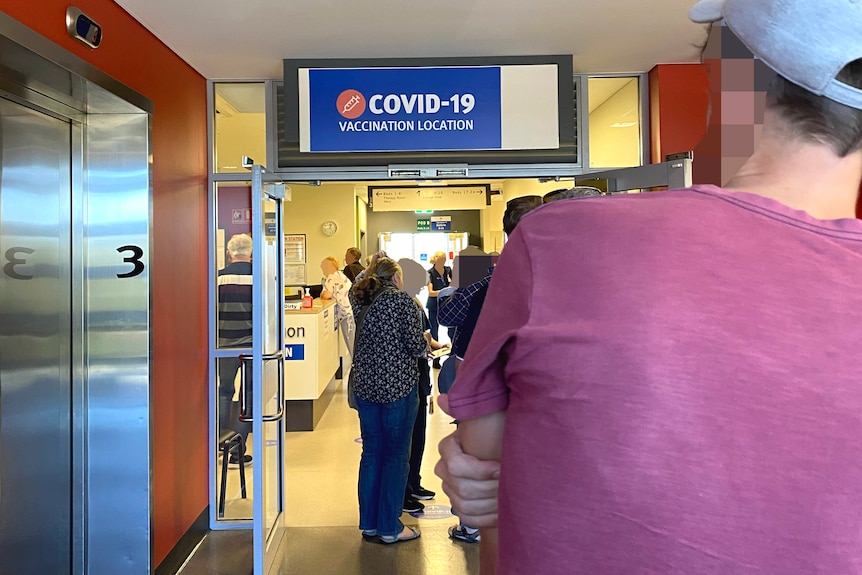 Line of people under COVID clinic sign