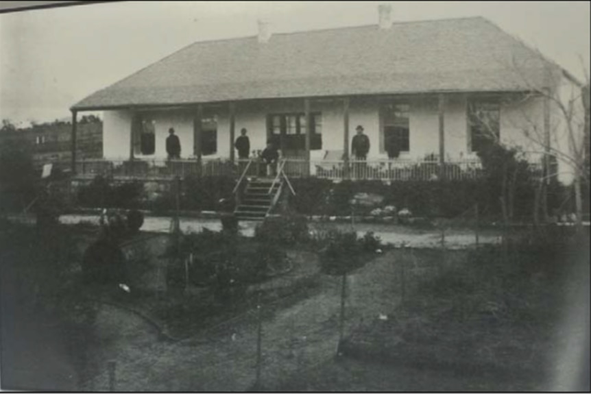 Black and white photo of house with people on verandah.