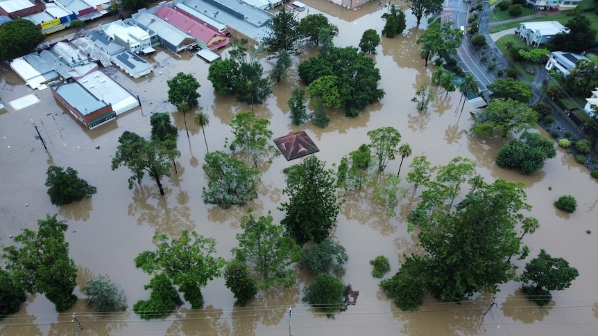 Properties under water in Gympie flooding event, aerial of flood water in businesses and one structure only roof is visible