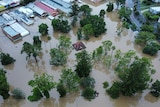 Properties under water in Gympie flooding event, aerial of flood water in businesses and one structure only roof is visible