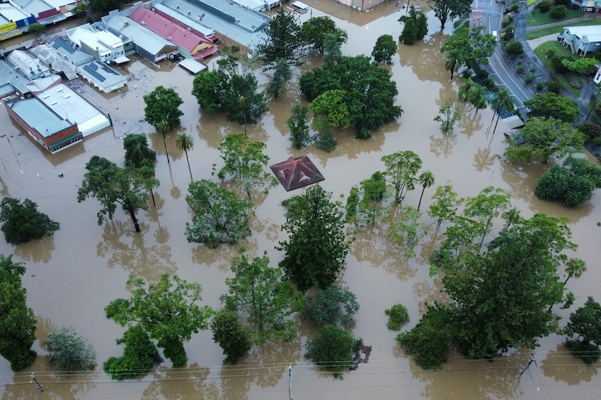 Properties under water in Gympie flooding event, aerial of flood water in businesses and one structure only roof is visible