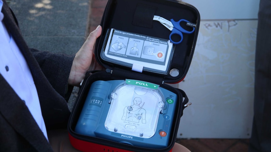 A man holding a portable defibrillator.