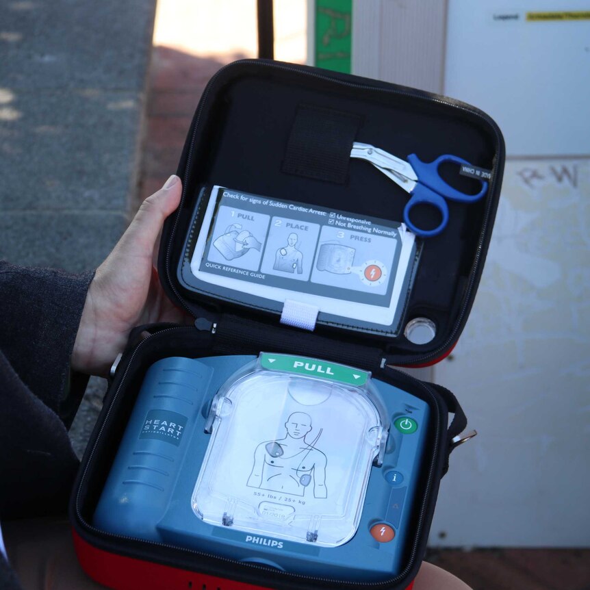 A man holding a portable defibrillator.