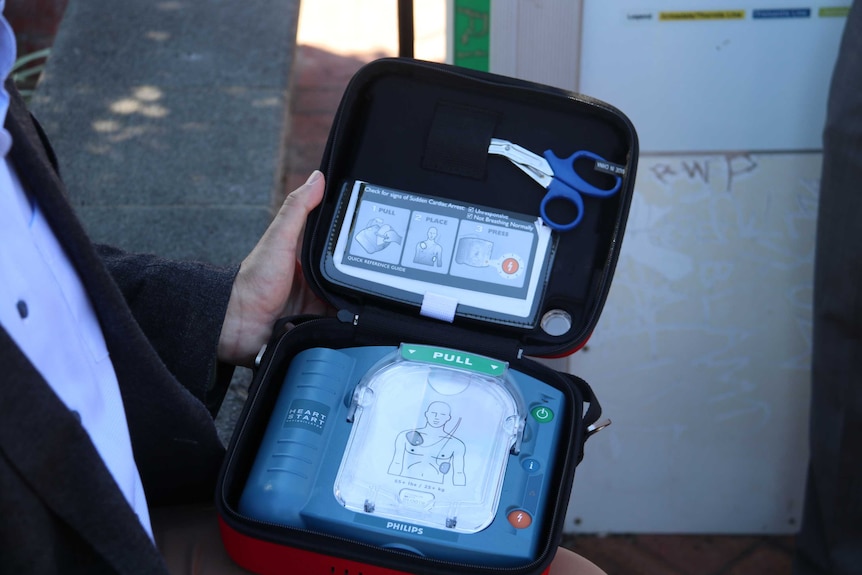 A man holding a portable defibrillator.